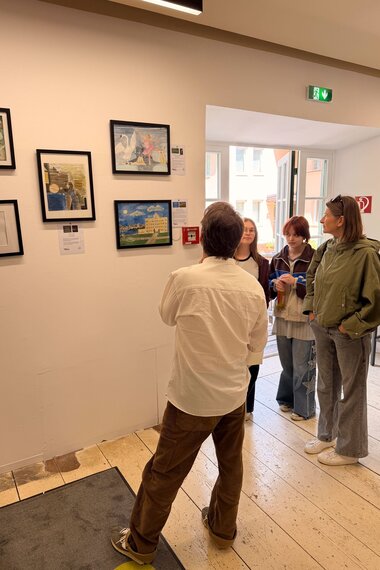 Salzwelten Altaussee Ausstellung Steinberghaus erster Stock vier Bilder an der Wand mit Personen welche sich darüber unterhalten  | © ©Salzwelten Grögler