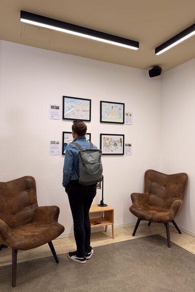 Salzwelten Altaussee Ausstellung Steinberghaus erster Stock vier Bilder im Hintergrund rechts und links Ledersessel Person im Zentrum begutachtet die Bilder | © ©Salzwelten Grögler 